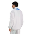 Rear view of a man wearing a light grey Adidas track jacket with blue accents and matching track pants against a plain white background.