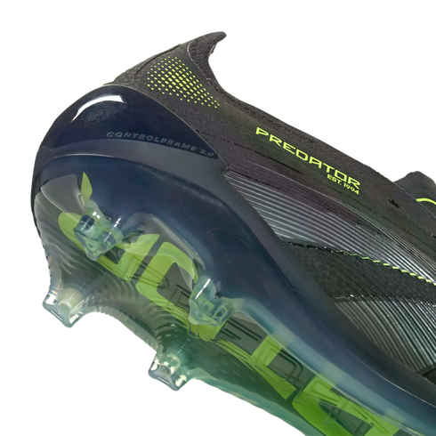 Close-up of a black Predator soccer cleat's heel and soleplate, featuring lime green accents and a translucent control frame with studs against a black background.