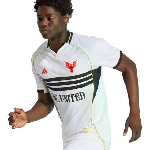 Young Black athlete in a white D.C. United soccer jersey with black stripes, gold trim, and a red eagle crest, captured mid-stride against a solid black backdrop.