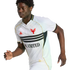 Young Black athlete in a white D.C. United soccer jersey with black stripes, gold trim, and a red eagle crest, captured mid-stride against a solid black backdrop.