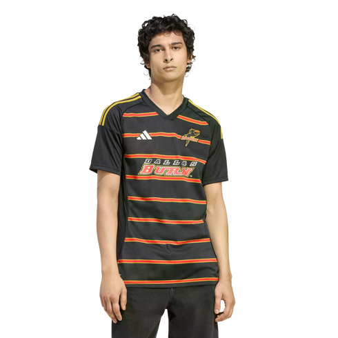 A man wears a black Dallas Burn soccer jersey with red and gold stripes and logos, set against a solid black background.