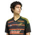 A young man with dark curly hair wearing a black Adidas Dallas Burn soccer jersey with red and yellow horizontal stripes, looking to the side.