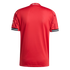 Rear view of a textured red football jersey with "Theatre of Dreams" on the collar and black-and-white striped cuffs, set against a black background.