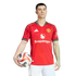 A man in a red Manchester United home jersey with the Snapdragon logo holds a soccer ball against a solid black background.