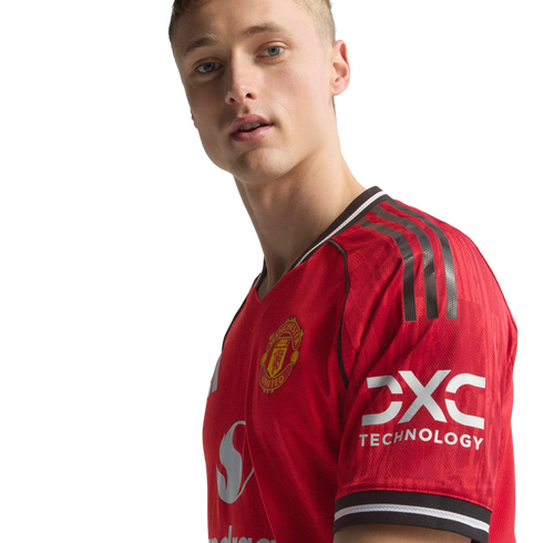 A blonde man wearing a red Manchester United football jersey with the club crest and sponsor logos against a black background.