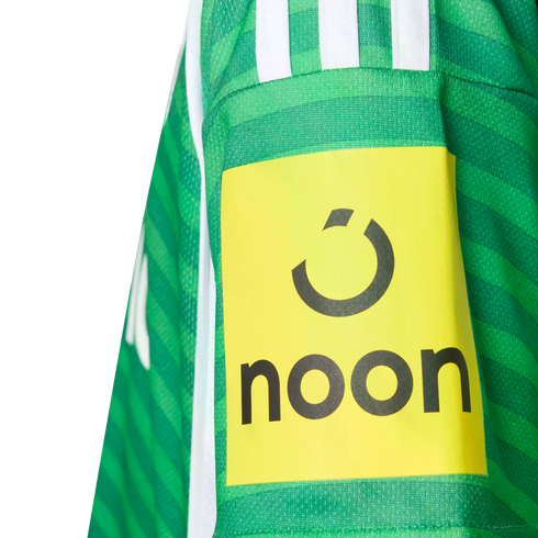 Close-up of a green striped sports jersey sleeve featuring a yellow patch with the black "noon" logo and brand icon.