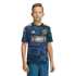 A youth stands wearing a navy blue and gold Philadelphia Union soccer jersey and blue jeans against a solid black background.