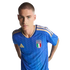 A man wearing a blue Italy national soccer team jersey with gold accents against a black background.