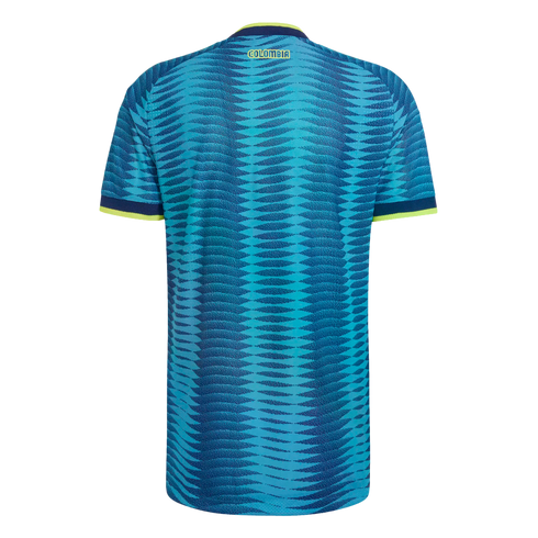 Back view of a blue Colombia soccer jersey featuring a wave pattern, yellow "COLOMBIA" text, and lime green trim on the collar and sleeves.