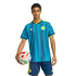 A man in a blue and teal patterned soccer jersey and matching shorts holds a colorful soccer ball against a solid black background.