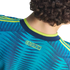 Back view of a person with curly hair wearing a teal patterned soccer jersey with yellow "COLOMBIA" text and lime green accents.