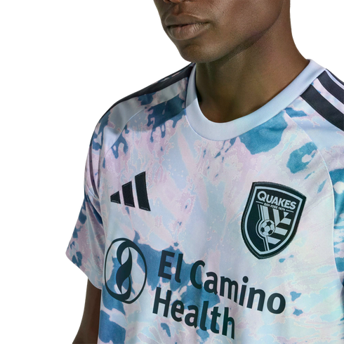 Close-up of a San Jose Earthquakes soccer jersey with a light blue and pink marbled pattern, featuring the Adidas logo, team crest, and El Camino Health sponsor logo.
