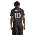 Back view of a man with dreadlocks wearing a black Inter Miami CF soccer jersey with "MESSI" and number "10" in pink. He is standing against a solid black background.