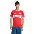 A man models a red Chicago Fire soccer jersey featuring a white chest band with the "CARVANA" logo, paired with blue jeans against a black background.