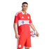 A male soccer player in a red Chicago Fire uniform holding a soccer ball against a black background.