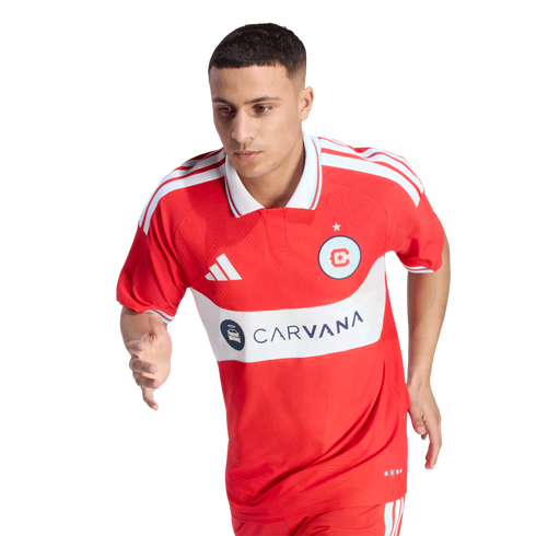 A male soccer player in a red Chicago Fire FC jersey with "CARVANA" logo, captured in a running pose against a black background.