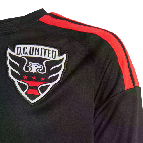 Close-up of a black D.C. United soccer jersey with red stripes on the shoulder and an embroidered team crest on the chest.