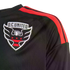Close-up of a black D.C. United soccer jersey with red stripes on the shoulder and an embroidered team crest on the chest.