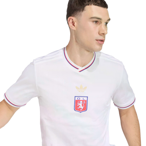 A man wearing a white Olympique Lyonnais soccer jersey with red and blue trim, looking sideways against a black background.