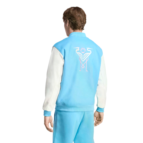 Back view of a man wearing a light blue and white varsity jacket with a stylized bird graphic on the back and matching light blue pants.