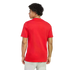 Rear view of a man with dark curly hair wearing a plain red T-shirt and light-colored pants, shown from the waist up against a black background.