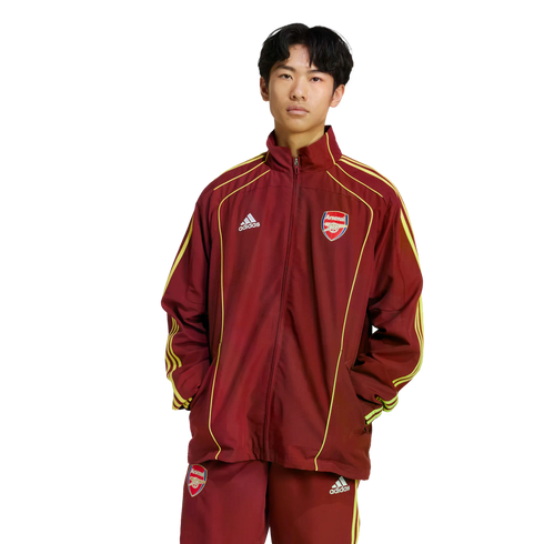 A person wearing a maroon and gold Adidas Arsenal football tracksuit, standing against a plain white background.