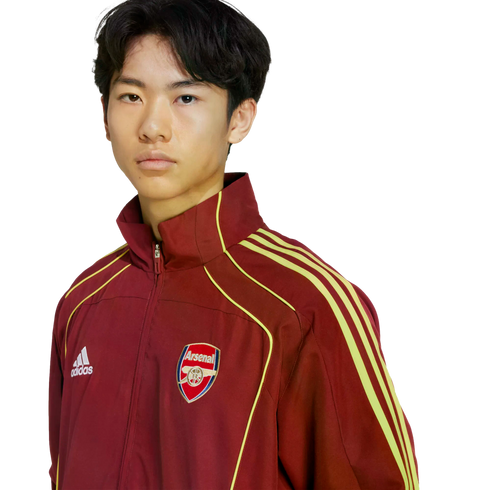 A young person with dark hair wearing a maroon Adidas tracksuit jacket featuring the Arsenal F.C. crest, set against a white background.