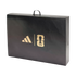 A black rectangular carrying case with a top handle features gold Adidas and FIFA World Cup 26 logos. The box has a subtle, intricate pattern on its surface.