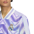 Close-up of a person wearing a purple Real Madrid soccer jersey with a geometric pattern, white stripes on the shoulders, and the team crest on the chest.