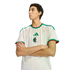 A man with crossed arms wearing an Algeria national team soccer jersey against a black background.