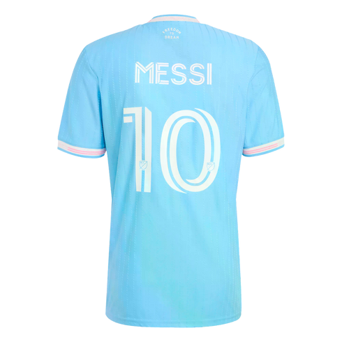 Back of a light blue soccer jersey with 'MESSI' and number '10' in white. It has pink accents on the sleeves and collar and 'Freedom to Dream' printed at the top center.