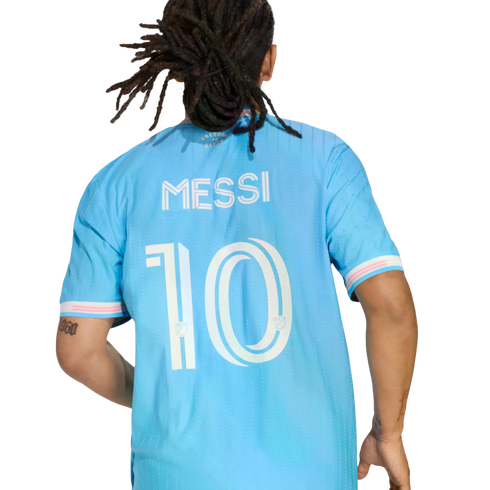 Back view of a person with dreadlocks wearing a light blue soccer jersey with the name 'MESSI' and number '10' printed on the back.