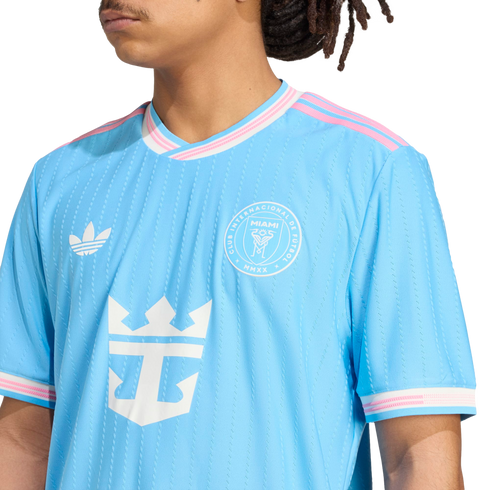Person wearing a light blue Inter Miami CF soccer jersey with white logos and pink-and-white striped trim on the collar and sleeves.
