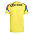 The back of a yellow soccer jersey featuring the black "Corona" logo across the upper back. The short sleeves have red, blue, and black geometric patterns and additional branding.