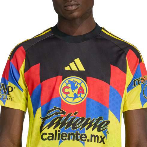 A person wearing a Club América soccer jersey with a black, yellow, red, and blue geometric pattern, featuring the team crest and various sponsor logos.