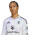A man in a white Manchester United long-sleeve jersey with a Snapdragon logo, posed against a black background.