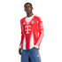 A Black man wearing a long-sleeved red and white Adidas FC Bayern Munich soccer jersey and blue jeans, standing with one hand in his pocket against a white background.
