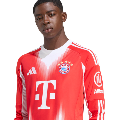 A young Black man wearing a red and white long-sleeved FC Bayern Munich soccer jersey with visible Adidas and T-Mobile logos against a white background.
