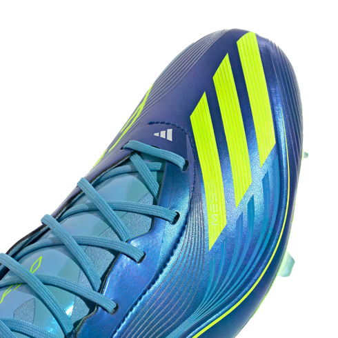 Close-up of a metallic blue Adidas soccer cleat with vibrant yellow stripes, light blue laces, and Messi branding.