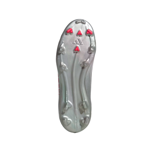 The metallic silver outsole of a soccer cleat with silver and bright pink chevron studs against a white background.