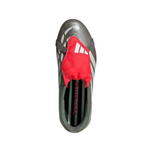 Top-down view of a grey Adidas Predator soccer cleat featuring a prominent red fold-over tongue with white stripes and an elastic strap over the laces.