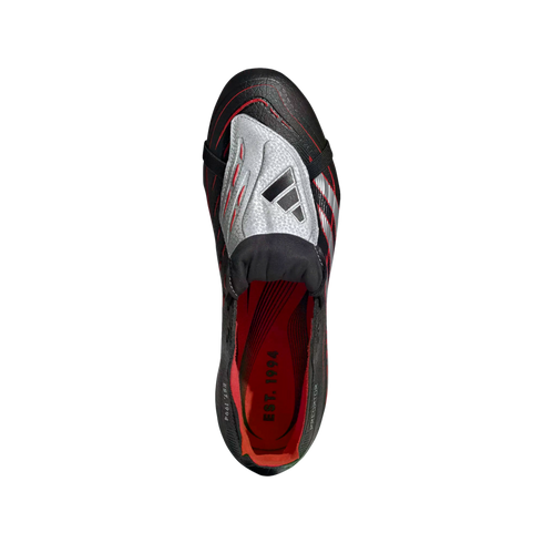 Top-down view of a black Adidas Predator soccer cleat with a silver fold-over tongue and a red interior featuring the text "EST. 1994."