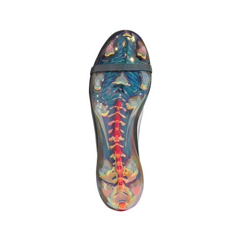 Bottom view of an iridescent soccer cleat soleplate with clear studs, a central red spine, and a grey elastic strap against a solid black background.