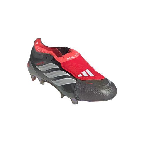 A black and red Adidas Predator soccer cleat with a red fold-over tongue and silver stripes on the side, set against a black background.