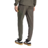 Rear view of a person wearing olive green athletic pants and jacket with black Adidas Samba sneakers.