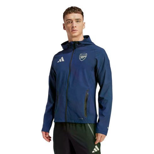 Man modeling a navy Adidas Arsenal FC hooded jacket and black training pants against a black background.