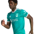 A young man in a teal Liverpool FC football jersey with white and black trim, posing in an athletic stance against a solid black background.