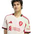 A young man with dark wavy hair wearing a white and red Liverpool FC soccer jersey, smiling against a plain black background.