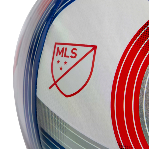 A close-up of a white soccer ball featuring a red MLS logo and curved blue and red graphics.
