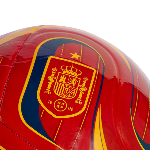 Close-up of a glossy red soccer ball featuring the Royal Spanish Football Federation crest in yellow and red, with a single gold star above it.
